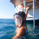 Person wearing a snorkeling mask in the water near a boat